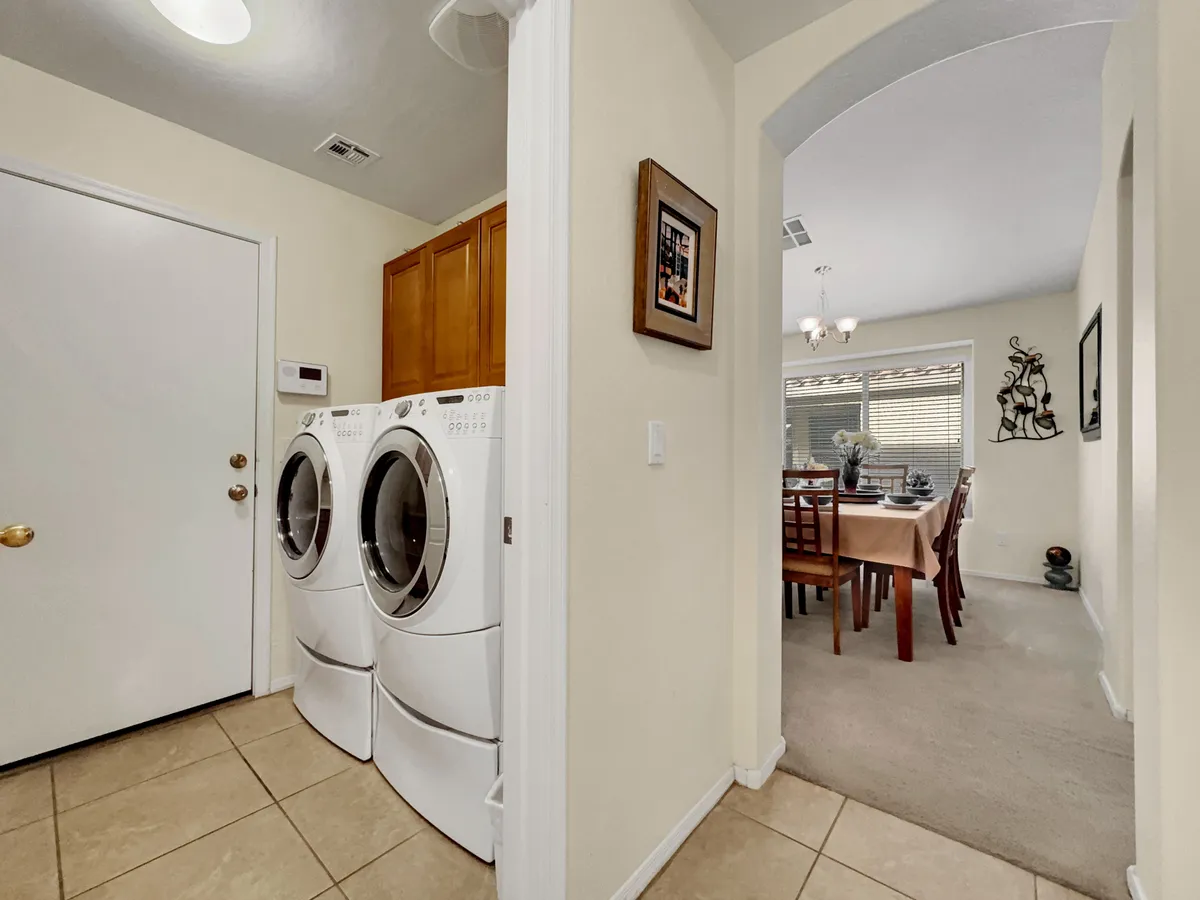 A functional laundry nook featuring a stacked washer and dryer next to a dining area, accented by framed artwork. This space is bright and accessible, offering day-to-day convenience for longer stays.