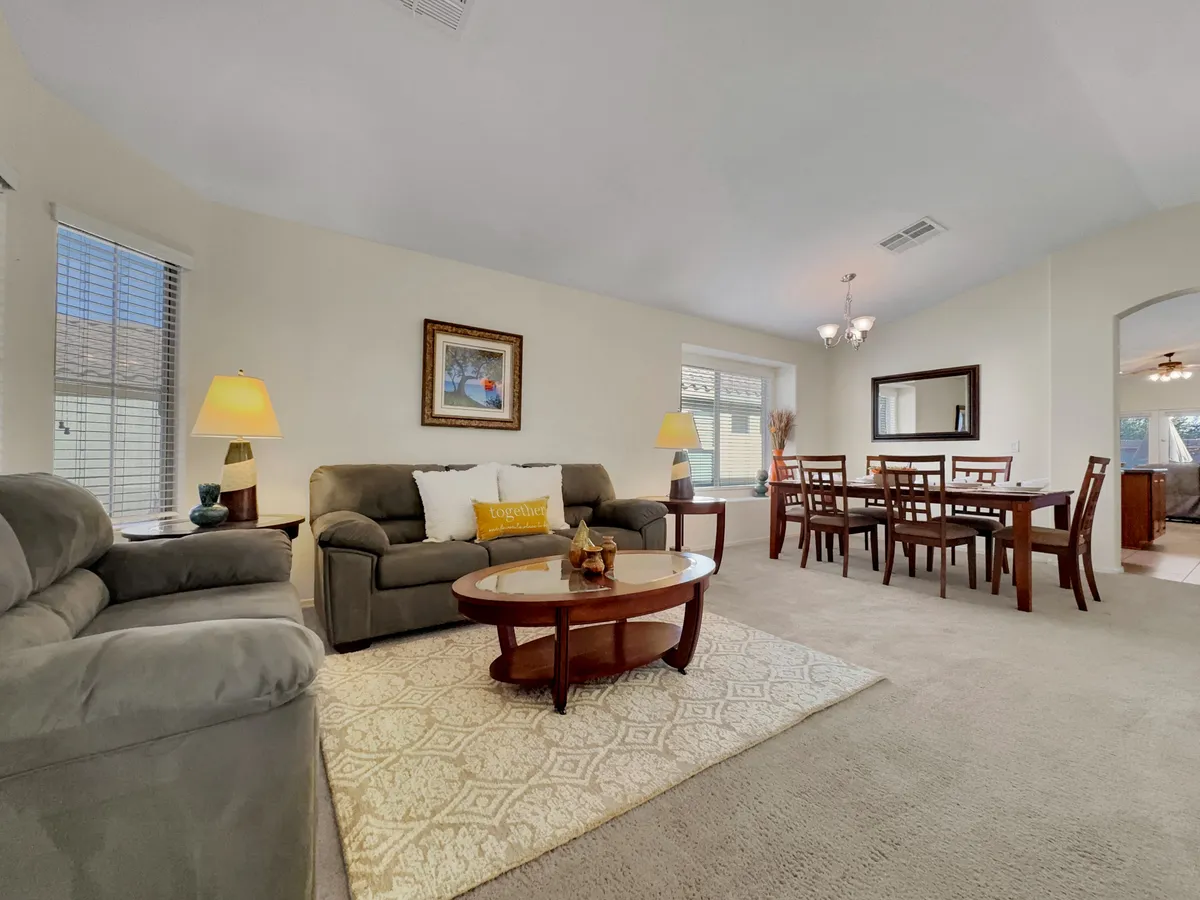 This image features a cozy and inviting living room with a plush sofa, stylish dining table, decorative artwork on the walls, and warm lighting fixtures. The space is arranged to encourage gatherings and conversation, evoking the camaraderie of friends relaxing after a day of golf.