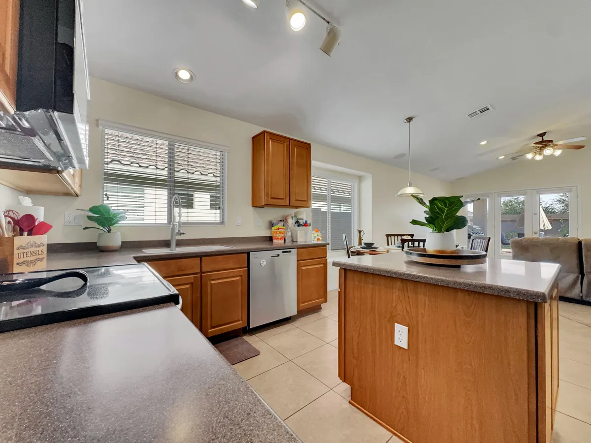 An open kitchen and dining area with a prominent kitchen island, stainless steel appliances, and large windows that fill the space with natural light. The adjacent dining area is visible, seamlessly connecting cooking and dining zones for family gatherings or casual meals.